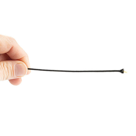 Een hand houdt een dunne, zwarte kevlar aramide vezel met een polyester mantel vast. De vezel is strak gespannen, met aan één uiteinde een kleine, gele kern die zichtbaar is door de zwarte mantel heen. De achtergrond is volledig wit.